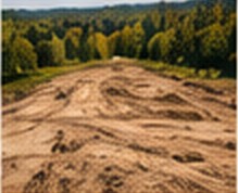 Graded vacant land with forested hills beyond
